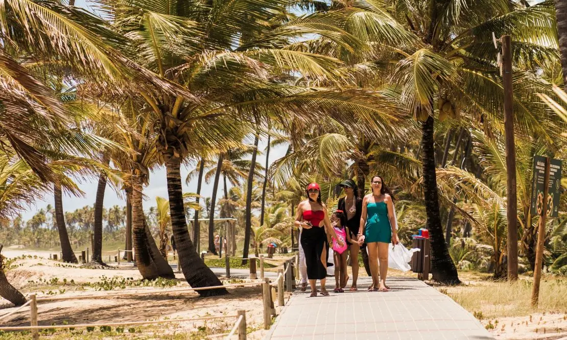 mulheres e uma criança caminhando pelo caminho de madeira que da acesso à praia da Costa do Sauípe Resorts