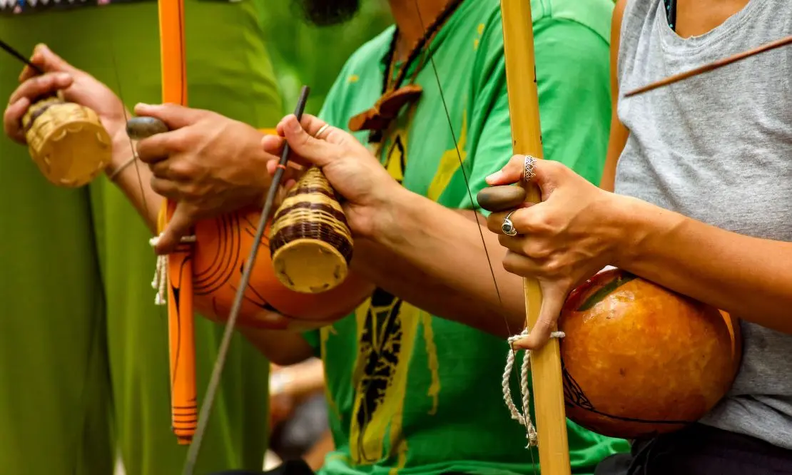 Pessoas que tocam berimbau em uma tradicional roda de capoeira