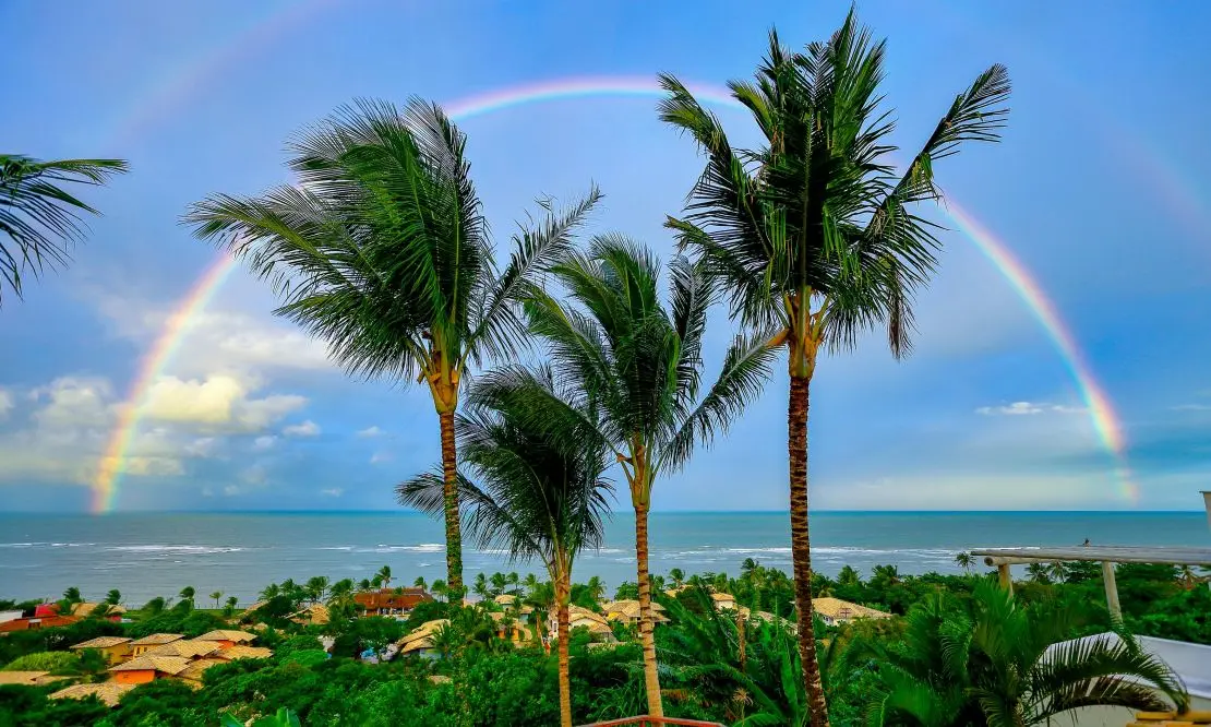 Praia de Arraial D'Ajuda com o mar ao fundo e um arco-íris sobre o mar