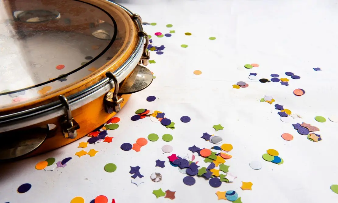 Pandeiro sobre uma mesa branca com confetes coloridos espalhados