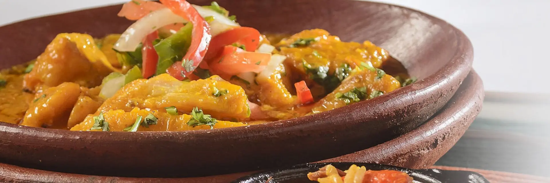 Imagem de um prato marrom em um fundo branco contendo uma receita das comidas típicas da Bahia