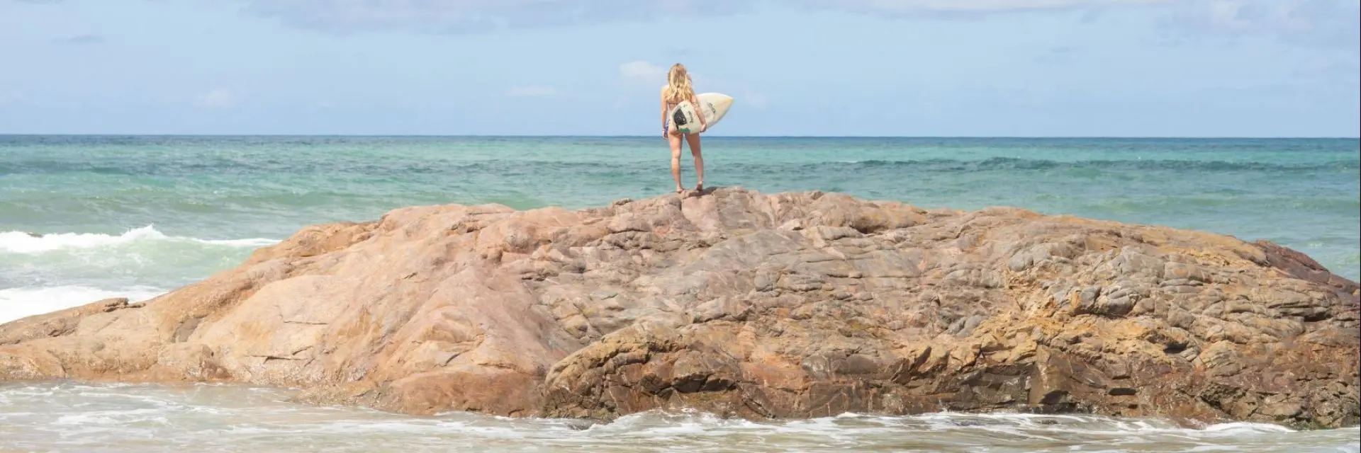 Imagem de uma pessoa com prancha em frente ao mar