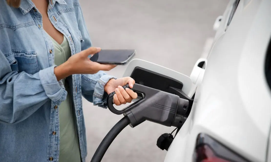 Pessoa segurando o cabo de carregamento de um carro elétrico