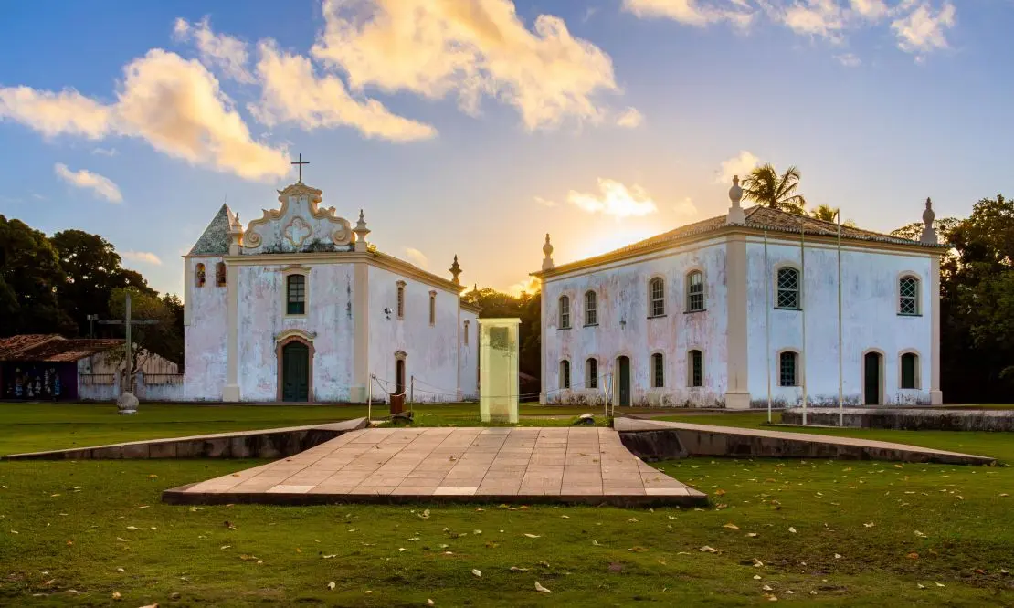 Museu histórico de Porto Seguro e a Igreja Nossa Senhora da Penha. Dois prédios antigos com o pôr do sol ao fundo