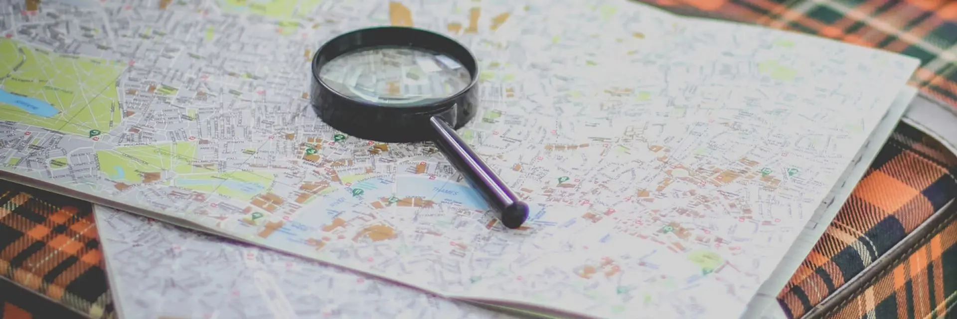 Imagem de uma mala de viagem com um mapa e uma lupa em cima dela