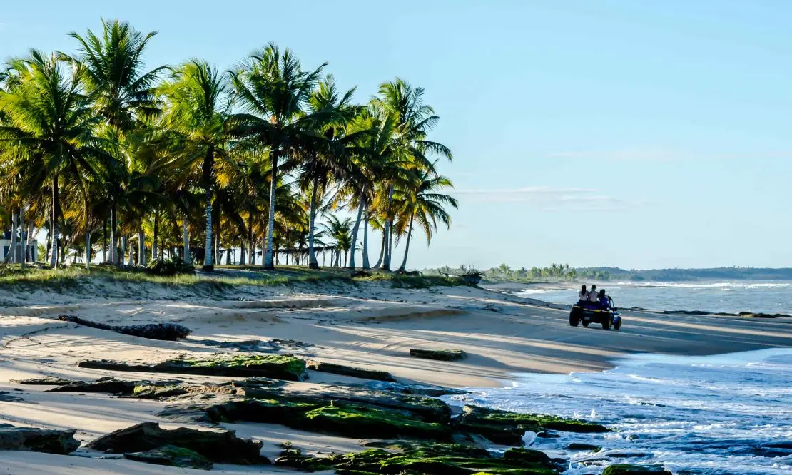 Buggy com algumas pessoas passeando pela orla de uma praia na Bahia