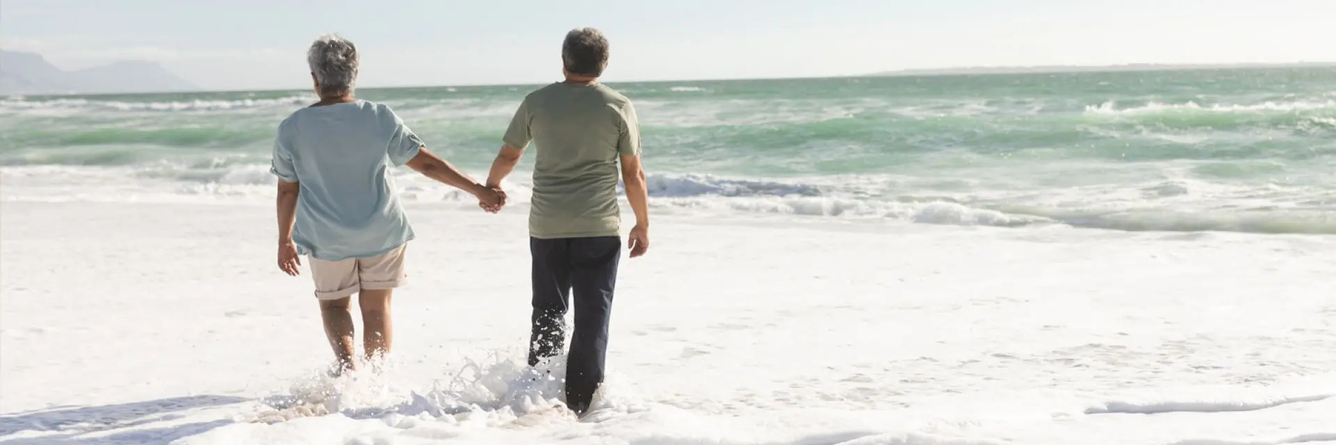 Imagem de dois adultos andando a beira-mar