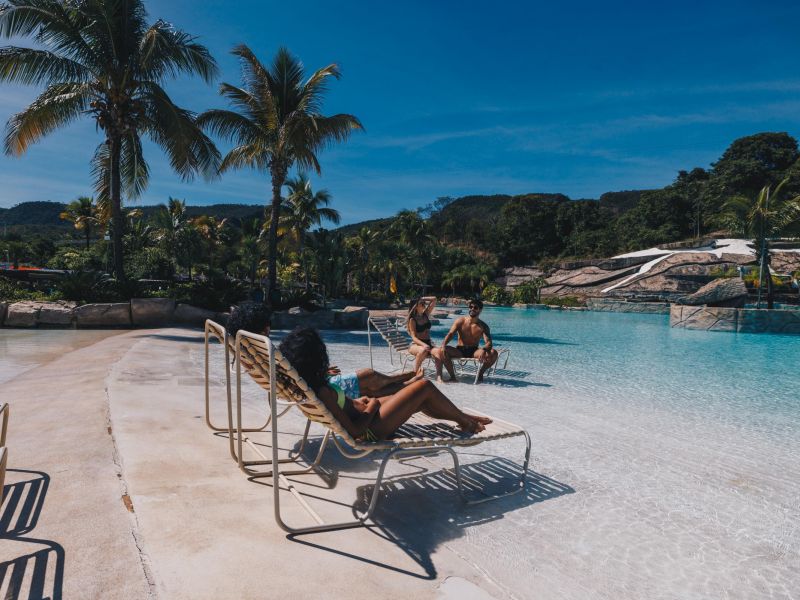 Pessoas deitadas em cadeiras de praia no meio da Praia do Cerrado, no Hot Park